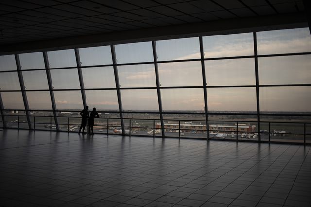 Travelers look out onto the tarmac of the OR Thambo International Airport in Johannesburg as restrictions on international flights from South Africa start to take effect, November 30th, 2021